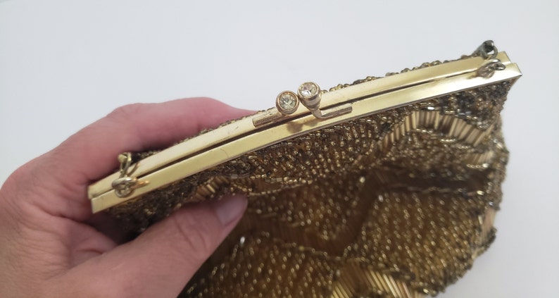 Pu&ograve; includere: Una borsa da sera in perline dorate con una chiusura in metallo dorato e due strass trasparenti. La borsa &egrave; realizzata con una fine rete di perline dorate.
