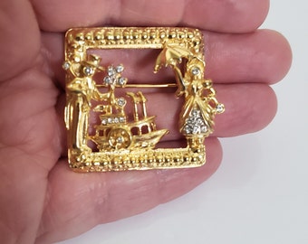 Broche de escena de tono dorado cuadrado vintage, pareja de cortejo y barco fluvial acentuado con pedrería de cristal