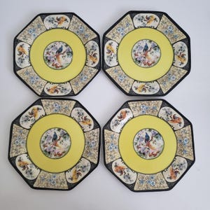 May include: Set of four yellow octagonal ceramic plates with a black border and a floral design featuring birds.