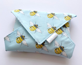 May include: A light blue fabric food wrap with a repeating pattern of yellow and black bees. The wrap is folded and has a white label that says "Tweedley Handmade".