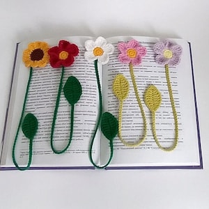 May include: Five crocheted flower bookmarks with green stems and leaves. The flowers are yellow, red, white, pink, and purple.