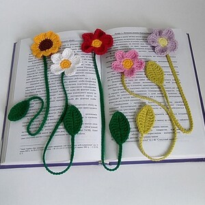 May include: Five crocheted flower bookmarks with green leaves. The flowers are yellow, white, red, pink, and purple.