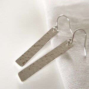May include: A pair of silver hammered bar earrings with a simple hook fastening.