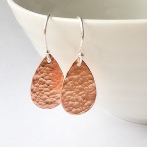 May include: A pair of hammered copper teardrop earrings with silver hooks.