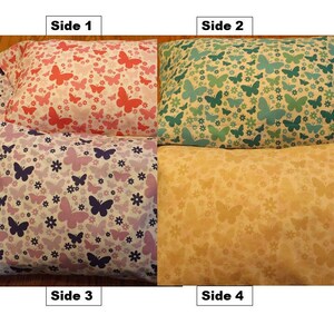 May include: Four-sided pillow with a different butterfly pattern on each side. The sides are pink with red butterflies, green with teal butterflies, purple with dark blue butterflies, and yellow with orange butterflies.