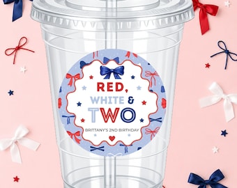 May include: Clear plastic cup with a lid and straw, decorated with a circular sticker. The sticker features the text "RED, WHITE & TWO" in red, white, and blue, with bow and star accents. The text "BRITTANY'S 2ND BIRTHDAY" is also included.