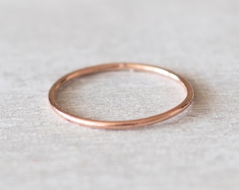 May include: A simple, thin rose gold band ring.