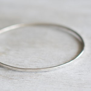 Peut inclure: Un bracelet jonc en argent simple, une pièce de joaillerie minimaliste.