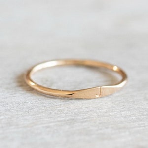 May include: A simple gold band ring with a hammered texture and a small letter "J" engraved on the side.