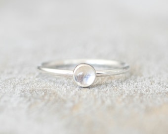 May include: A silver ring with a round, white gemstone.