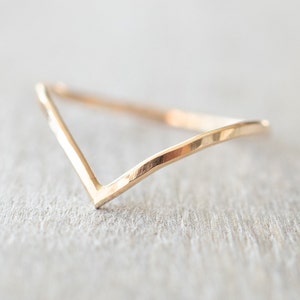 Puede incluir: Un anillo de banda de oro simple con un dise&ntilde;o en forma de V. El anillo est&aacute; hecho de metal martillado, lo que le da un aspecto texturizado.