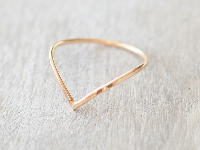 Puede incluir: Un anillo de oro simple con un dise&ntilde;o en forma de V. El anillo est&aacute; hecho de metal martillado, lo que le da un aspecto texturizado.