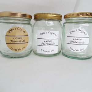 May include: Three glass jars with gold lids and brown labels. The labels say "Rita's Organic Lemon Marmalade Spread the love".