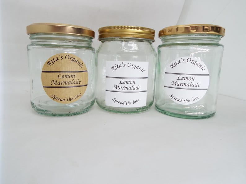 May include: Three glass jars with gold lids and brown labels. The labels say "Rita's Organic Lemon Marmalade Spread the love".