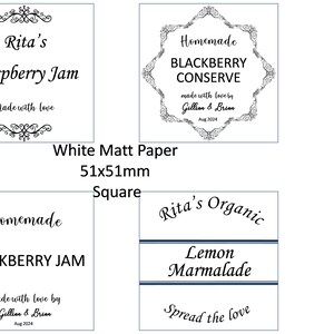 May include: Four white square labels with black text and decorative flourishes. The labels are for homemade jams and marmalades. The labels read: "Rita's Raspberry Jam", "Homemade Blackberry Conserve", "Homemade Blackberry Jam", and "Rita's Organic Lemon Marmalade".