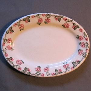 May include: White oval serving platter with a pink and green floral design around the edge.