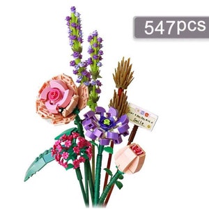 Könnte beinhalten: Ein Strauß bunter LEGO-Blumen, darunter rosa Rosen, lila Blumen und eine kleine Gruppe rosa Blumen. Der Strauß enthält auch einen grünen Stiel mit Blättern und ein kleines Schild mit der Aufschrift "Start A New Day With A Smile".