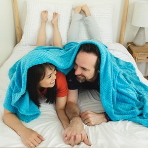 Picture of a couple holding hands under a blue blanket