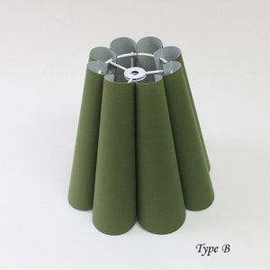 May include: A green lampshade with a pleated design. The lampshade is made of fabric and has a white metal frame. The lampshade is labeled "Type B".