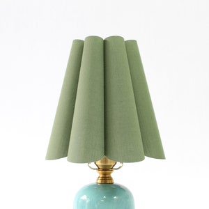 May include: A green pleated lampshade with a brass base and a light blue ceramic lamp body.