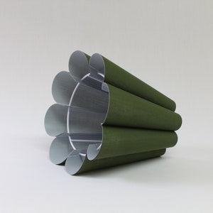 May include: A green pleated lampshade with a white interior. The lampshade is made of fabric and has a slightly textured surface.