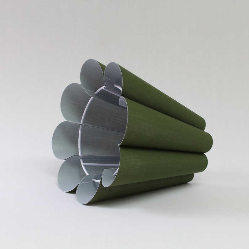 May include: A green pleated lampshade with a white interior. The lampshade is made of fabric and has a slightly textured surface.