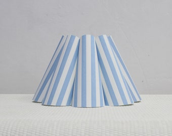May include: A blue and white striped lampshade with a conical shape.