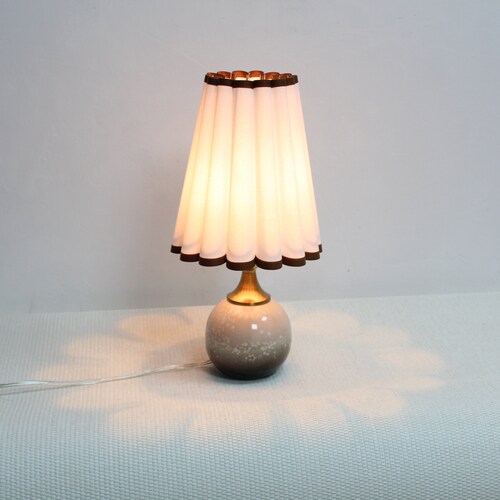 Handgemaakte lamp uit coquillestof: keramische basis met bruine rand, neutrale verlichting