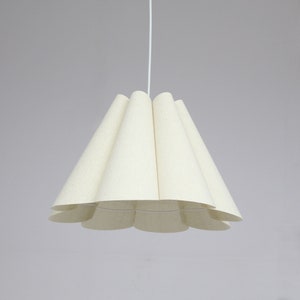 May include: A white pendant light with a pleated fabric shade. The shade is shaped like a flower with multiple petals.