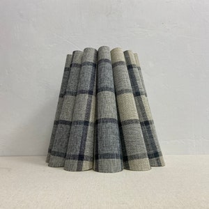 May include: A lampshade made of fabric with a black and white plaid pattern. The lampshade is pleated and has a rounded shape.