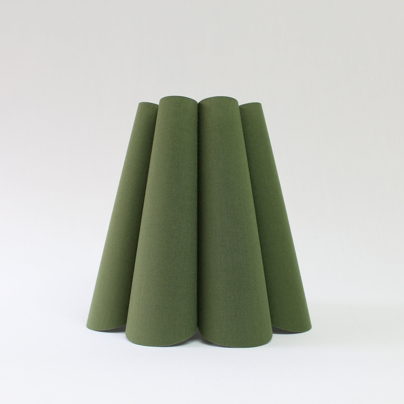 May include: A green lampshade with a pleated design. The lampshade is made of fabric and has a rounded shape.