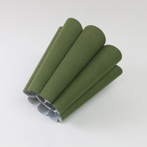 May include: A green lampshade made of fabric with a pleated design.