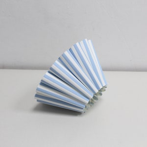Pu&ograve; includere: Un cono di carta a strisce blu e bianche piegato a forma di ventaglio. Il cono &egrave; fatto di carta e ha uno sfondo bianco con strisce blu.