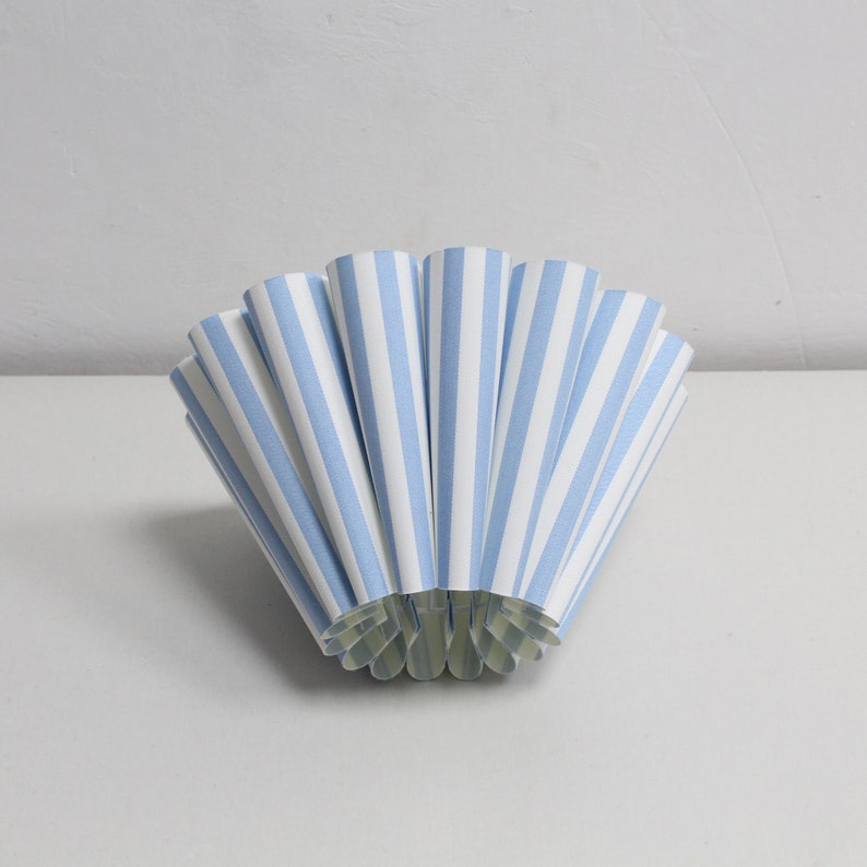 Pu&ograve; includere: Un ventaglio di carta blu e bianco, piegato a forma di cono.