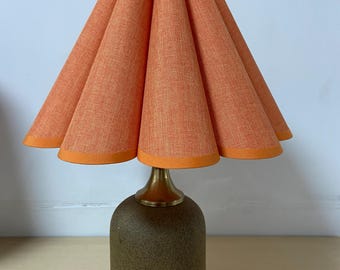 May include: A table lamp with a brown ceramic base and a pleated orange fabric lampshade.