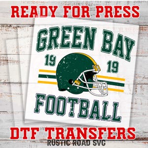 Op de afbeelding: Een wit vierkant ontwerp met de rode woorden "READY FOR PRESS" bovenaan en "DTF TRANSFERS" in het rood onderaan. Het ontwerp toont de groene woorden "GREEN BAY FOOTBALL" met een groene en gouden voetbalhelm.
