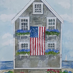 May include: A watercolor painting of a gray wooden house with white windows and a porch. The house is decorated with blue and green flowers in window boxes and an American flag hanging on the front. The house is set against a blue sky and ocean background.