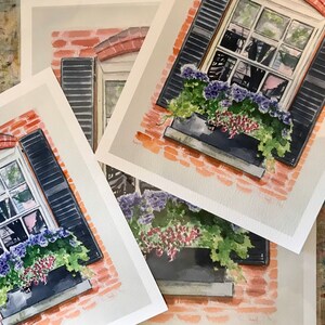 May include: Four watercolor paintings of a brick building with a window and flower box. The window has black shutters and the flower box is filled with purple and red flowers. The paintings are on white paper.