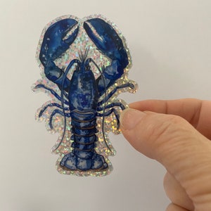 May include: A blue lobster sticker with a glittery background. The lobster is depicted in a realistic style with detailed claws and antennae.