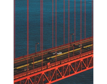 May include: A red metal bridge with a road and cars driving across it. The bridge is over a body of water, and the sky is blue.