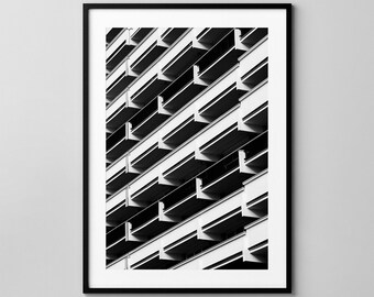 May include: Black and white architectural photograph of a building's facade. The image features a repeating pattern of balconies and horizontal lines, creating a geometric design. The photograph is framed in a black border.
