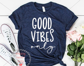 May include: Navy blue t-shirt with the words "GOOD VIBES only" in white script. The shirt is styled with white sneakers, a bouquet of pink and white roses, and a "CUTTING FILE" banner.