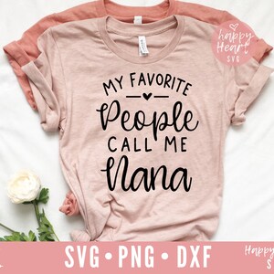 Puede incluir: Una camiseta rosa con el texto "My Favorite People Call Me Nana" en letras negras. La camiseta est&aacute; sobre una superficie blanca con una flor blanca.