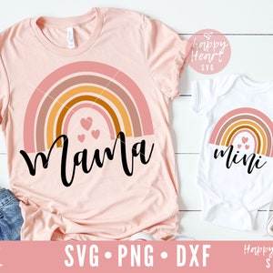 May include: A set of two shirts featuring a rainbow with hearts and the words "mama" and "mini". The shirts are pink and white.