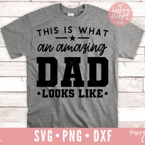 K&ouml;nnte beinhalten: Ein graues T-Shirt mit schwarzem Text, der "Das ist, wie ein gro&szlig;artiger Vater aussieht." lautet.