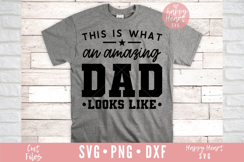 K&ouml;nnte beinhalten: Ein graues T-Shirt mit schwarzem Text, der "Das ist, wie ein gro&szlig;artiger Vater aussieht." lautet.