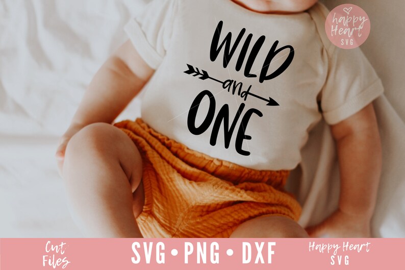 K&ouml;nnte beinhalten: Ein Baby tr&auml;gt einen wei&szlig;en Strampler mit dem Text "WILD and ONE" in schwarzen Buchstaben und einer Pfeilgrafik. Das Baby tr&auml;gt eine orangefarbene Hose und liegt auf einer wei&szlig;en Oberfl&auml;che.