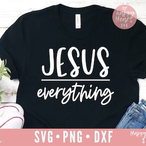 May include: A black t-shirt with the text "JESUS everything" in white lettering. The shirt is laid flat on a wooden surface.