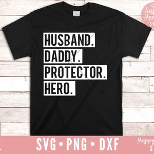 May include: Black t-shirt with white text that reads "Husband. Daddy. Protector. Hero."