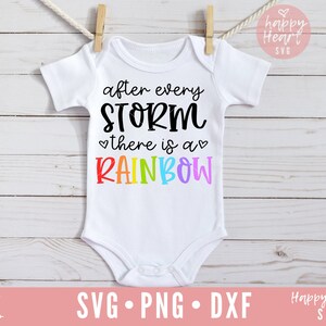 May include: White baby onesie with the text "after every STORM there is a RAINBOW" in black and rainbow colors. The onesie is hanging on a clothesline.